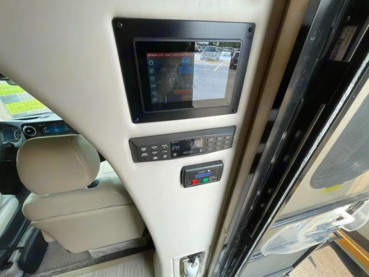 RV rental interior: Overhead cabin control panel with a large screen displaying exterior view and system controls near driver's seat.. Thor Delano 2021