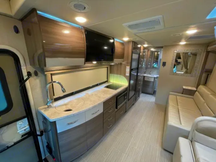 Spacious, modern RV rental interior with a fully equipped kitchen, comfy seating, and bathroom access. Ready for your next adventure!. Thor Delano 2021