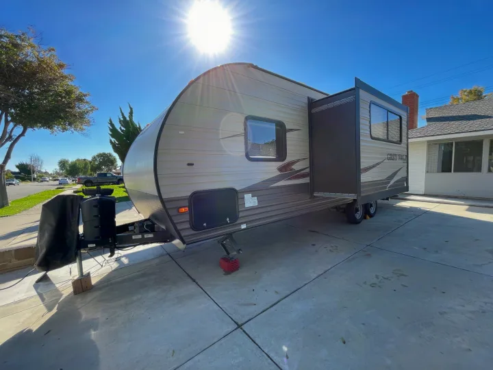 Sunny day: a "Grey Wolf" travel trailer RV rental, with slide-out extended, parked on a concrete driveway.. Forest River Cherokee Grey Wolf 2017