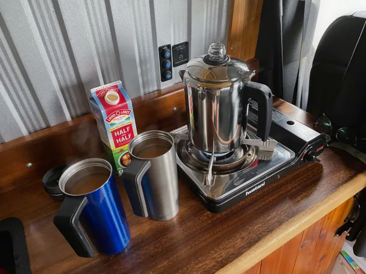 Morning coffee setup in an RV rental: percolator brewing on a portable stove, with mugs and half & half ready.. Mercedes Sprinter 2017