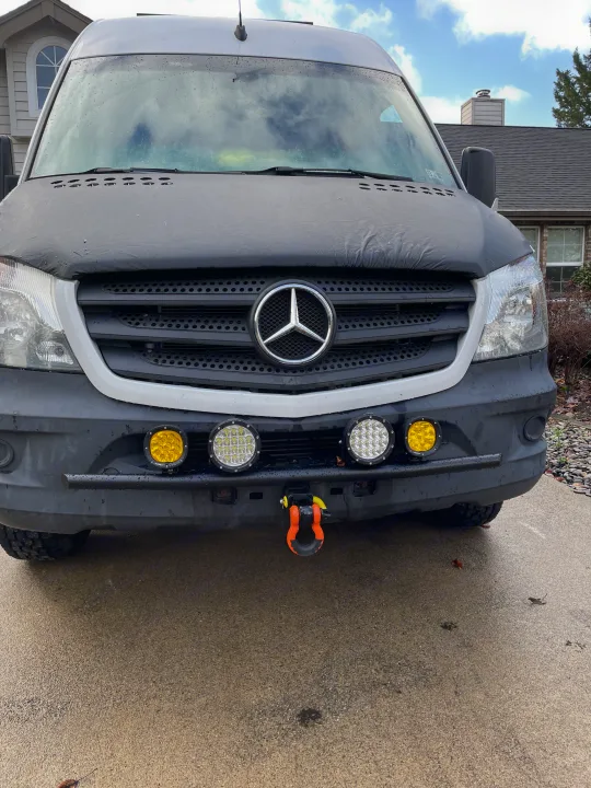 Front of a grey Mercedes Sprinter RV rental van. Features auxiliary lights, tow shackle, and a dark hood cover.. Mercedes Sprinter 2017