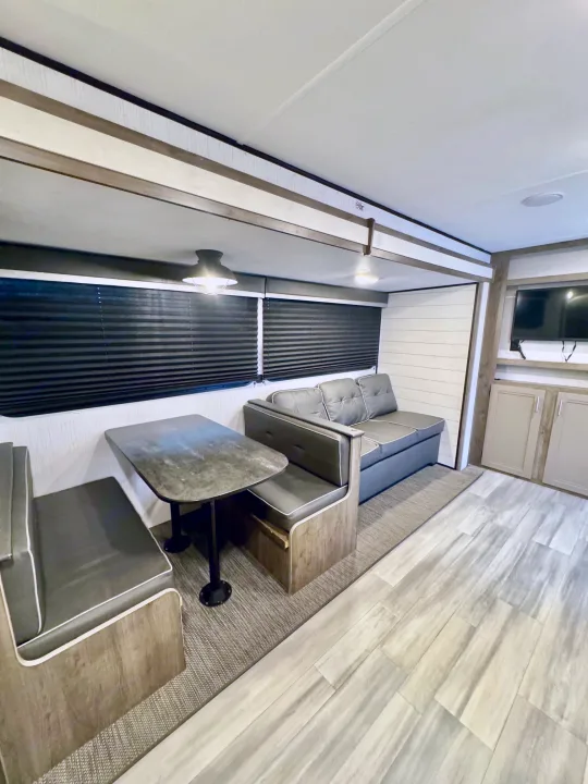 Spacious RV rental interior with a dinette, pull-out sofa, and TV area. Modern design ideal for trips.. Heartland RVs Pioneer 2021