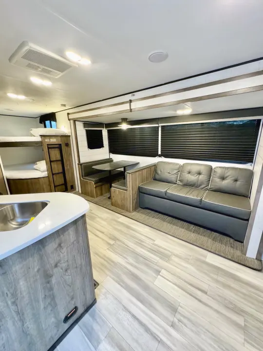 This rv rental features a kitchen counter, bunk beds, dining booth, and a sofa within its spacious interior.. Heartland RVs Pioneer 2021