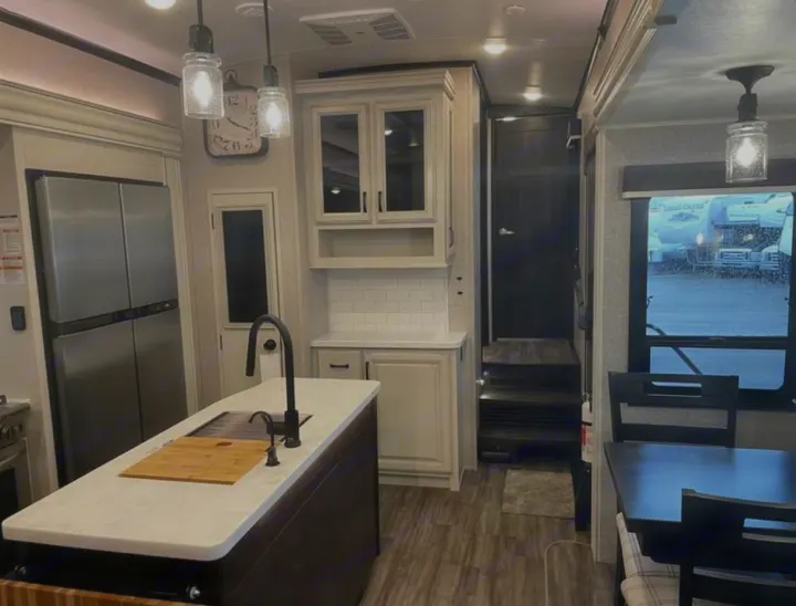 Explore this bright RV rental interior: spacious kitchen with island, stainless fridge, and a cozy dining area.. Jayco North Point 2023
