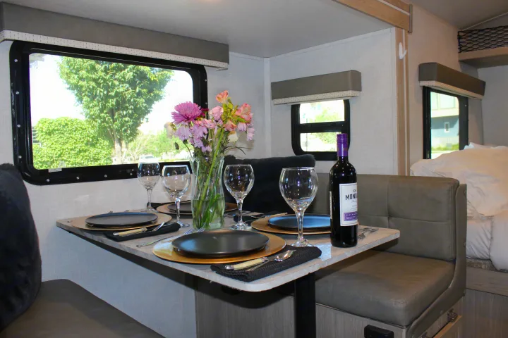 Cozy RV rental dining area set for four with wine and flowers, inviting for meals on your next adventure.. Forest River GeoPro 2021