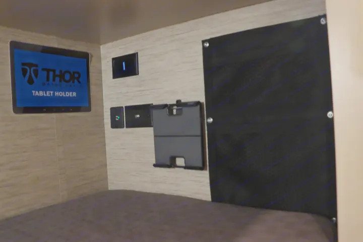 RV rental bunk area features a screen (Thor Motor Coach), tablet holder, charging ports, and a storage net.. Thor Freedom Elite 2023