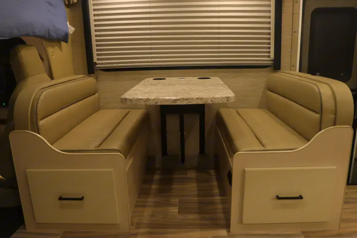 RV rental dinette area: cozy interior with two bench seats, a table, and window blinds.. Thor Freedom Elite 2023