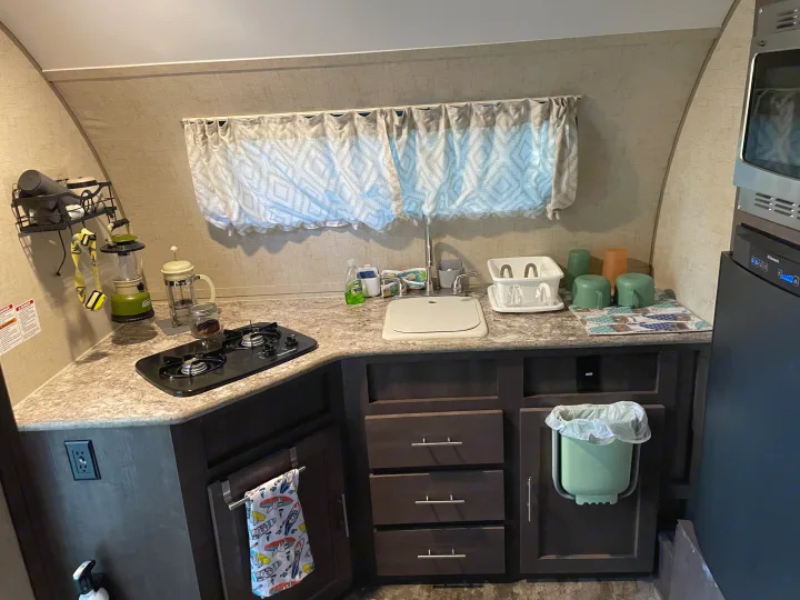 Compact RV rental kitchen with a sink, two-burner stove, countertop, and storage cabinets for essentials.. R-Pod Hood River Edition 2016
