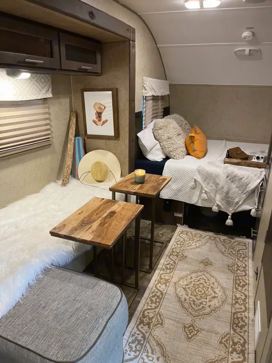 Inviting RV rental interior: cozy bed with pillows, faux fur bench, and warm wooden side tables.. R-Pod Hood River Edition 2016