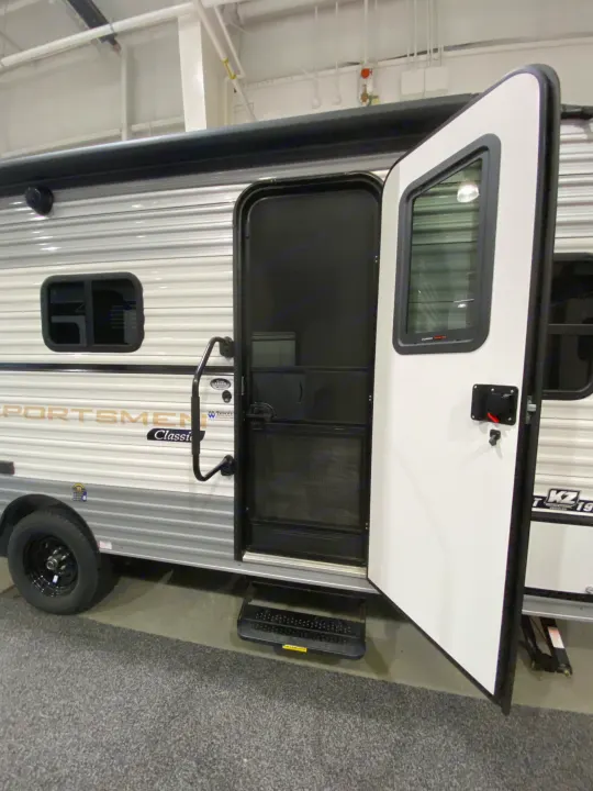 Explore this white Sportsmen Classic travel trailer with its door and screen door open, showcasing steps. Great for your next RV rental adventure.. KZ Sportsmen Classic 180BH 2024