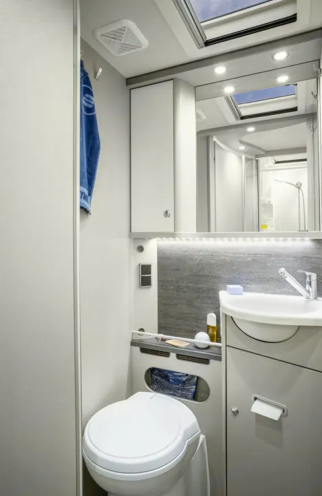 Clean, compact RV rental bathroom with toilet, sink, mirrored cabinet, and shower visible in reflection.. Hymer Exis I 678 2024