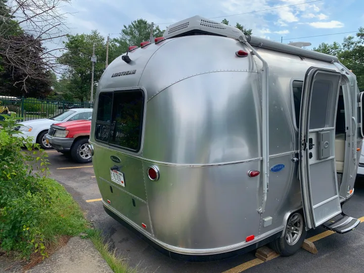 This iconic silver Airstream travel trailer, a great RV rental option, is parked with its door open for adventure.. Airstream Sport 2019
