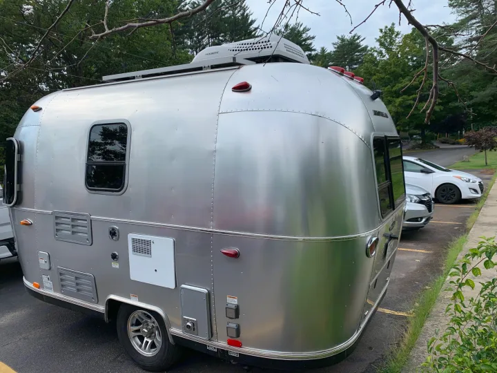 A sleek, silver Airstream travel trailer with a Dometic AC unit on top, seen here, often rented as an RV rental.. Airstream Sport 2019