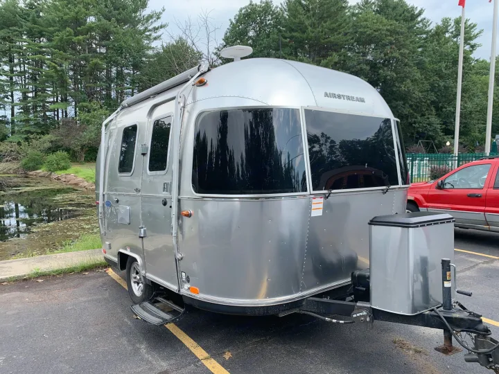 Airstream RV rental: Silver travel trailer, parked by a pond with tall trees. Perfect for your next adventure.. Airstream Sport 2019