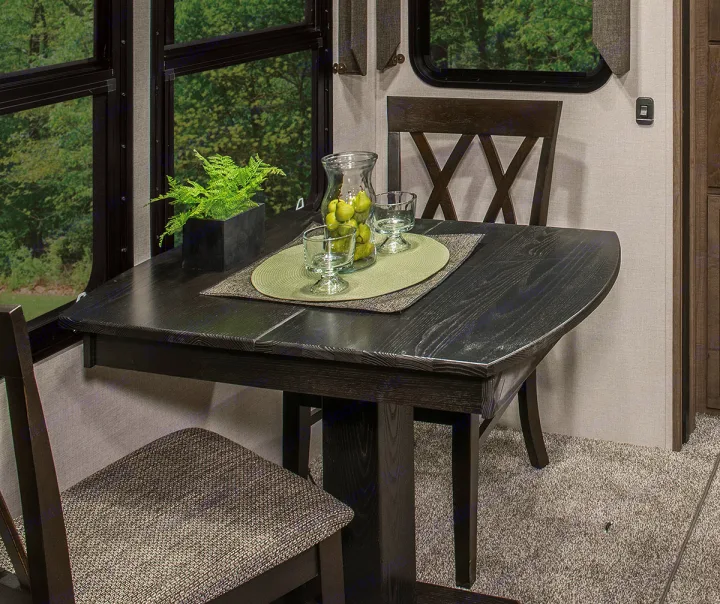 Cozy RV rental dining nook with a dark wood table, chairs, and scenic window views for comfortable travel.. K-Z Manufacturing Durango 2017