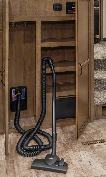 An rv rental's convenient central vacuum, with its hose ready, stored neatly in wood cabinets next to carpeted stairs.. K-Z Manufacturing Durango 2017