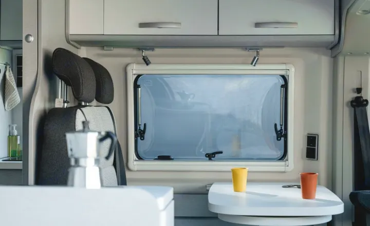 Relaxing rv rental interior features a window, dinette table with cups, and overhead storage. Ideal for road trip adventures.. Hymer FREE 600 CAMPUS 2024