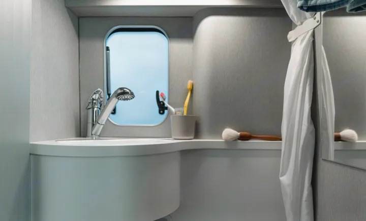 Inside a modern RV rental: compact bathroom with sink, versatile pull-out shower, small window, and daily essentials.. Hymer FREE 600 CAMPUS 2024