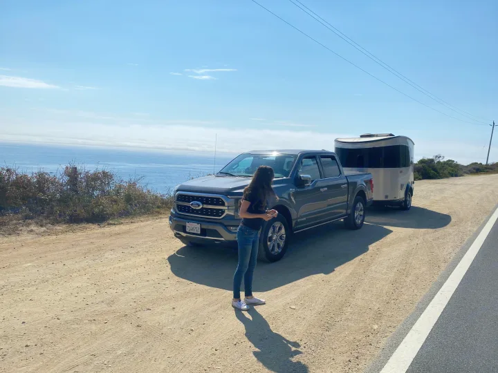 Scenic stop with our RV rental: a Ford truck towing a silver travel trailer overlooking the ocean.. Airstream Basecamp 2017