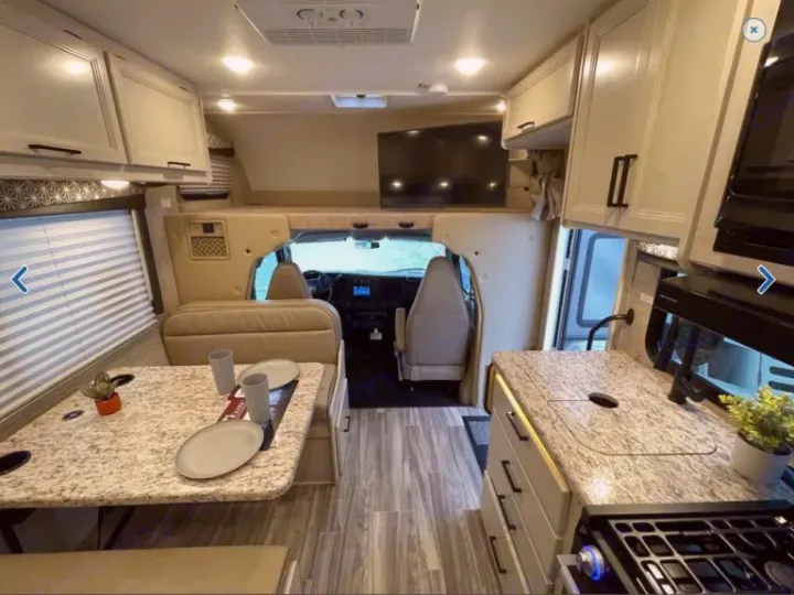 Spacious RV rental interior with modern kitchen, dining area, and bed over the cab, perfect for comfortable road trips.. Thor Freedom Elite 2023