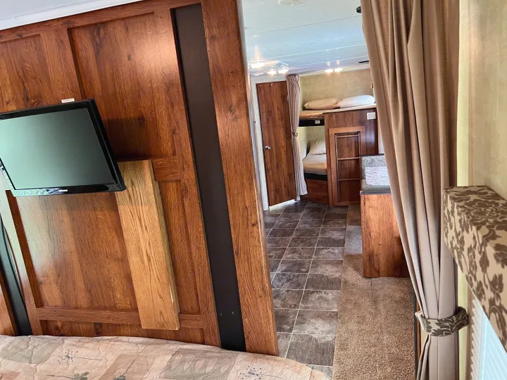 Interior of an RV rental showing a living space with TV, looking towards bunk beds and a side room. Cozy for your next adventure.. Keystone Hideout LHS 2014