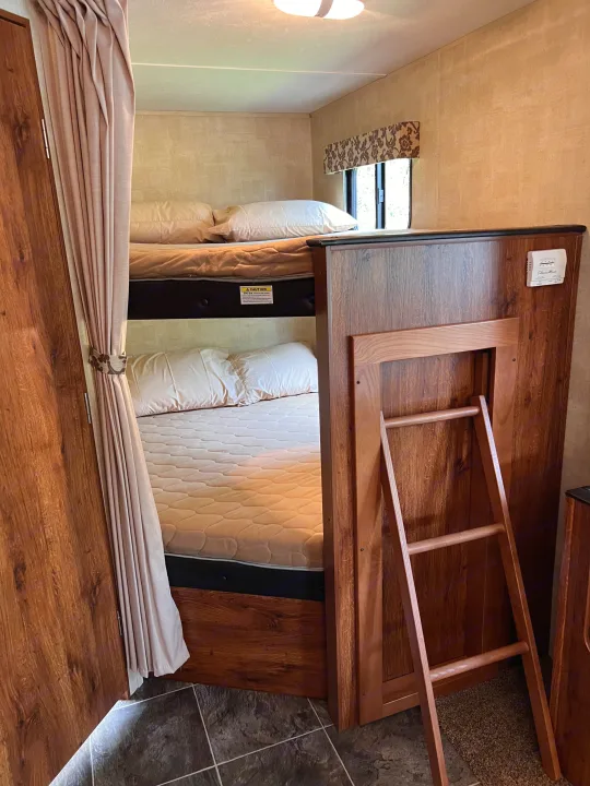 RV rental interior with comfortable bunk beds for sleeping, including mattresses, pillows, and a wooden ladder.. Keystone Hideout LHS 2014