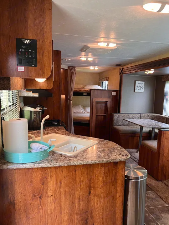 An inviting RV rental interior showcases a functional kitchen with sink, bunk beds, and a cozy dining area.. Keystone Hideout LHS 2014