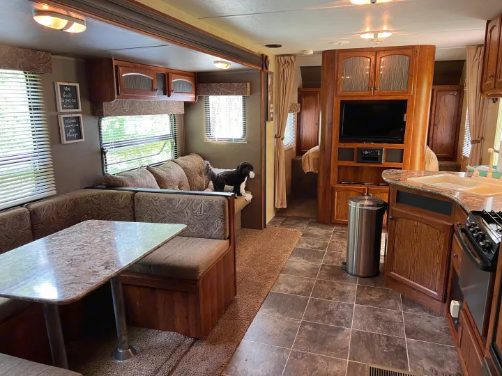 Spacious RV rental interior with a cozy dinette, well-equipped kitchen, and a cute dog enjoying the living space.. Keystone Hideout LHS 2014