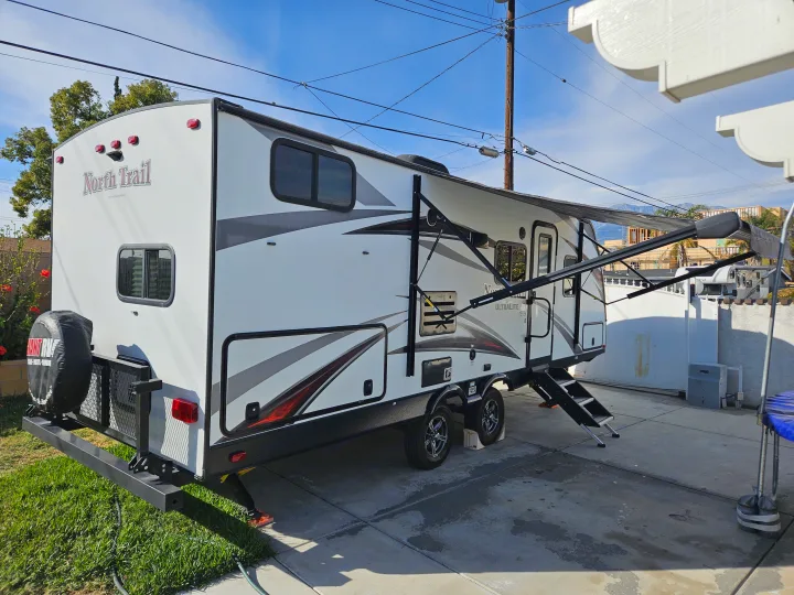 White North Trail travel trailer RV parked outdoors with awning extended. Perfect for your next rv rental trip!. Heartland RVs North Trail 2019