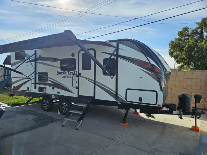 White North Trail travel trailer, ideal for your next rv rental trip. Awning extended, parked on concrete.. Heartland RVs North Trail 2019