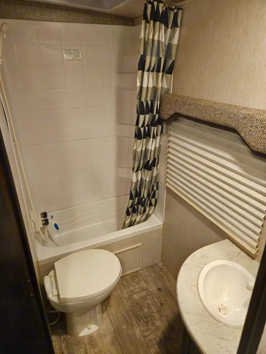 Compact rv rental bathroom featuring a toilet, shower, and sink, perfect for on-the-go travel and efficient living.. Heartland RVs North Trail 2019