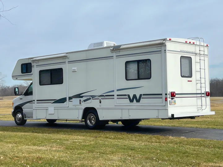 White Winnebago Class C RV, ideal for your next rv rental adventure, parked on a driveway.. Winnebago Minnie 2002
