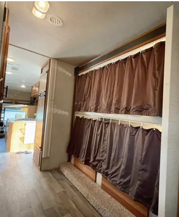 Inside this RV rental: comfortable bunk beds with privacy curtains, a bright living space, and wood flooring.. Jayco Redhawk 2017