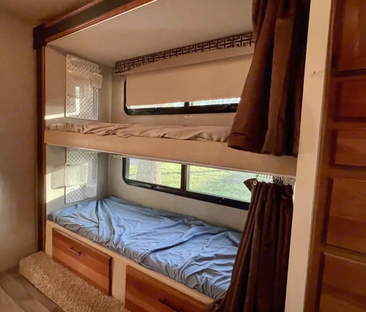 RV rental: Compact bunk beds with windows, custom pegboard storage, and privacy curtains, perfect for family comfort.. Jayco Redhawk 2017