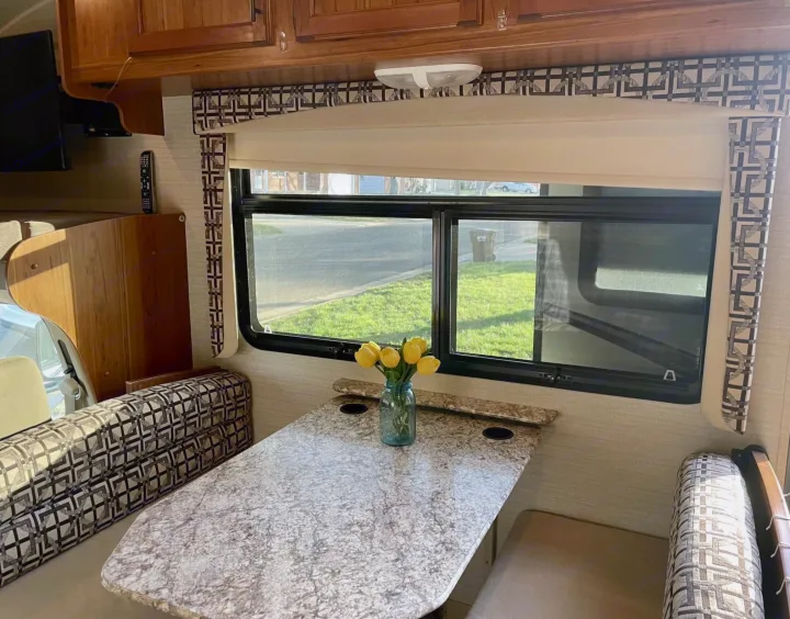 Inside this rv rental: a comfortable dinette area with a speckled table, patterned benches, and a wide window for views.. Jayco Redhawk 2017