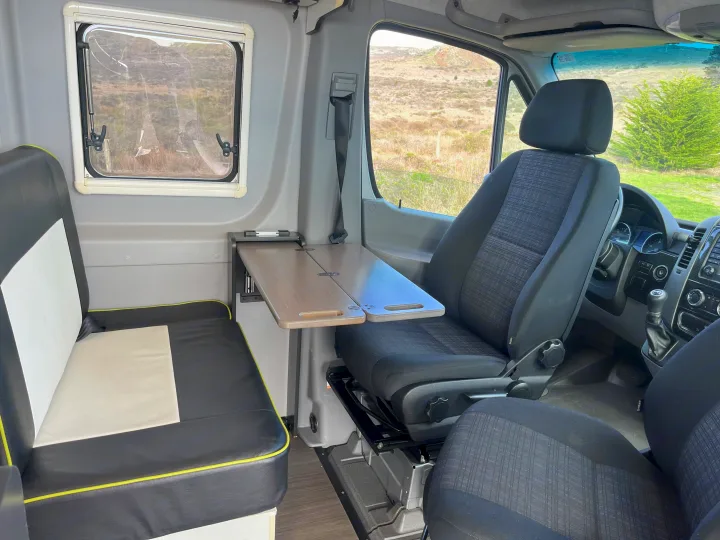 RV rental interior: a practical camper van setup with comfortable bench seating, a foldable table, and a scenic window view.. Winnebago Revel 2019