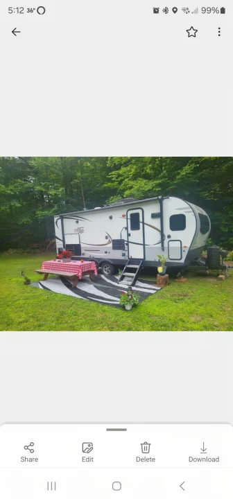 Relaxing outdoor rv rental setup with a white travel trailer, picnic table, and rug on green grass, surrounded by trees.. Forest River Rockwood Mini Lite 2021