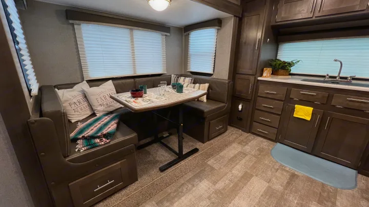 Cozy RV rental interior featuring a dinette with bench seating and a compact kitchen area with a sink and cabinets.. Forest River Rockwood Mini Lite 2021