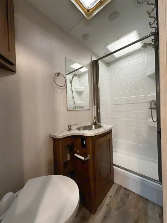 Bright RV rental bathroom featuring a glass shower, vanity with sink, toilet, and modern finishes, perfect for travel comfort.. Forest River Coachmen Pursuit 2020