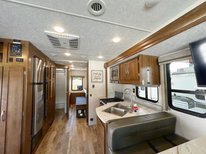 Spacious RV rental interior featuring a full kitchen, dining nook, and comfortable living area. Ideal for travel.. Forest River Coachmen Pursuit 2020