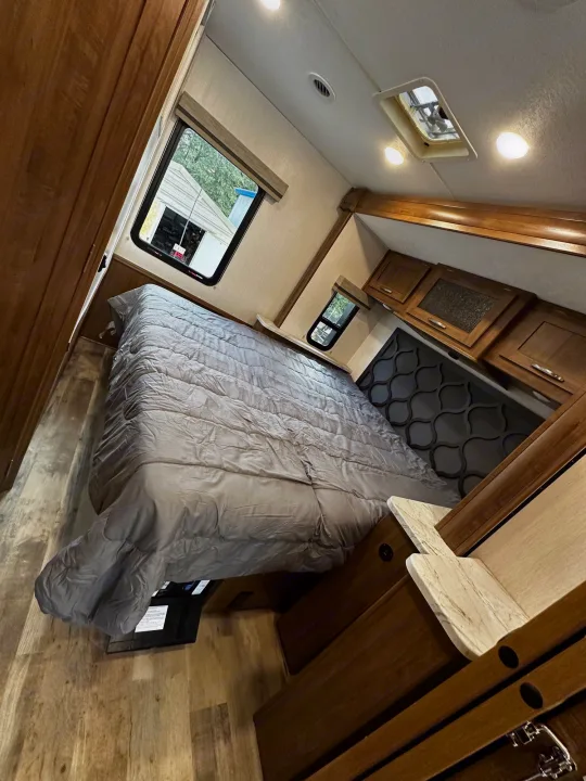 Spacious RV rental bedroom with a comfy bed, wood cabinets, and large windows. Ready for your adventure!. Forest River Coachmen Pursuit 2020
