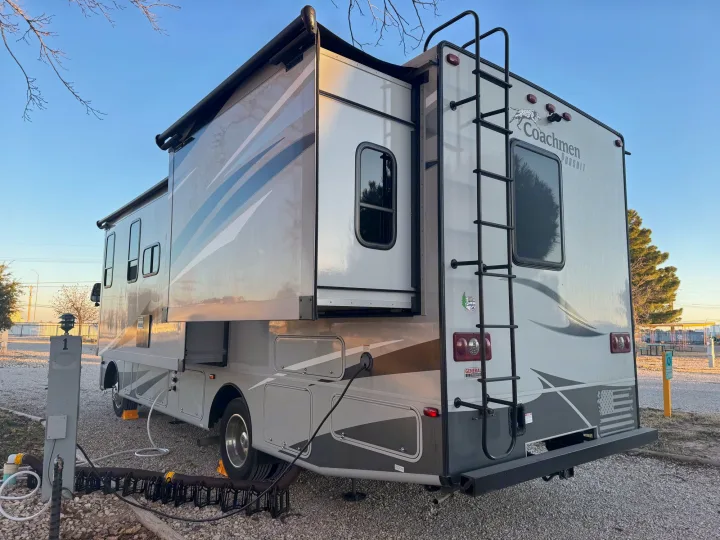 Grey rv rental with slide-out extended, parked at a sunny campsite, connected to utilities. Ready for travel.. Forest River Coachmen Pursuit 2020