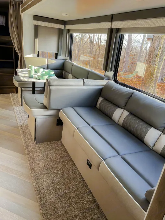 Spacious RV rental interior with modern U-shaped dinette, sofa, and large windows offering scenic outdoor views.. Forest River Salem 2022