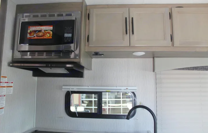 RV rental kitchen: convection microwave, cabinets, window, and sink faucet create a compact cooking area.. Freelander Coachman 2023