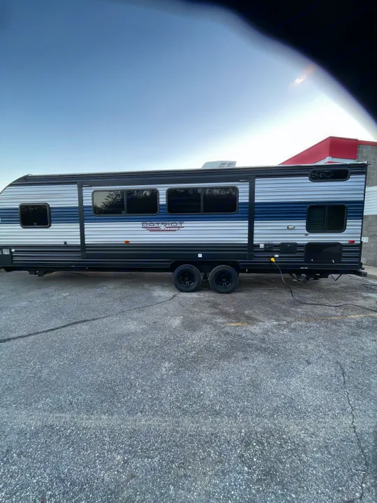 Explore with this striped blue & white Patriot Edition travel trailer, an ideal RV rental for your next adventure. Power connected.. Forest River Patriot 26DBH 2022
