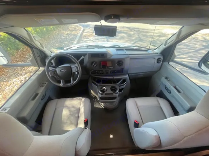 RV rental: Inside view of the front driving area, revealing the dashboard, steering wheel, and two comfortable seats.. Coachmen FREELANDER 2025