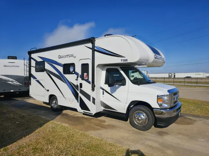 A white Thor Quantum LC Class C RV with blue accents, seen from the front side, perfect as an rv rental.. Thor Quantum LC 2024