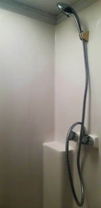 A clean, compact shower stall in an RV rental, featuring a handheld showerhead, flexible hose, and water controls. Ideal for travel.. Ice Castle Fish Houses Ice Castle Fish Houses Trailer 2016
