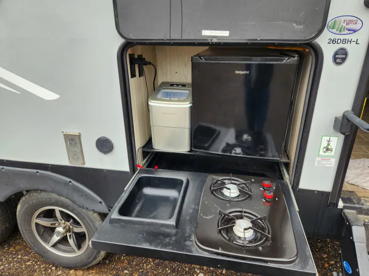 RV rental outdoor kitchen: 2-burner stove, sink, Contoure ice maker, and Hotpoint mini-fridge for easy outdoor cooking.. Forest River Cherokee Alpha Wolf 2020