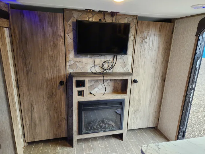 Experience comfort in this RV rental's living area, complete with a wall-mounted TV, electric fireplace, and storage cabinets.. Forest River Cherokee Alpha Wolf 2020